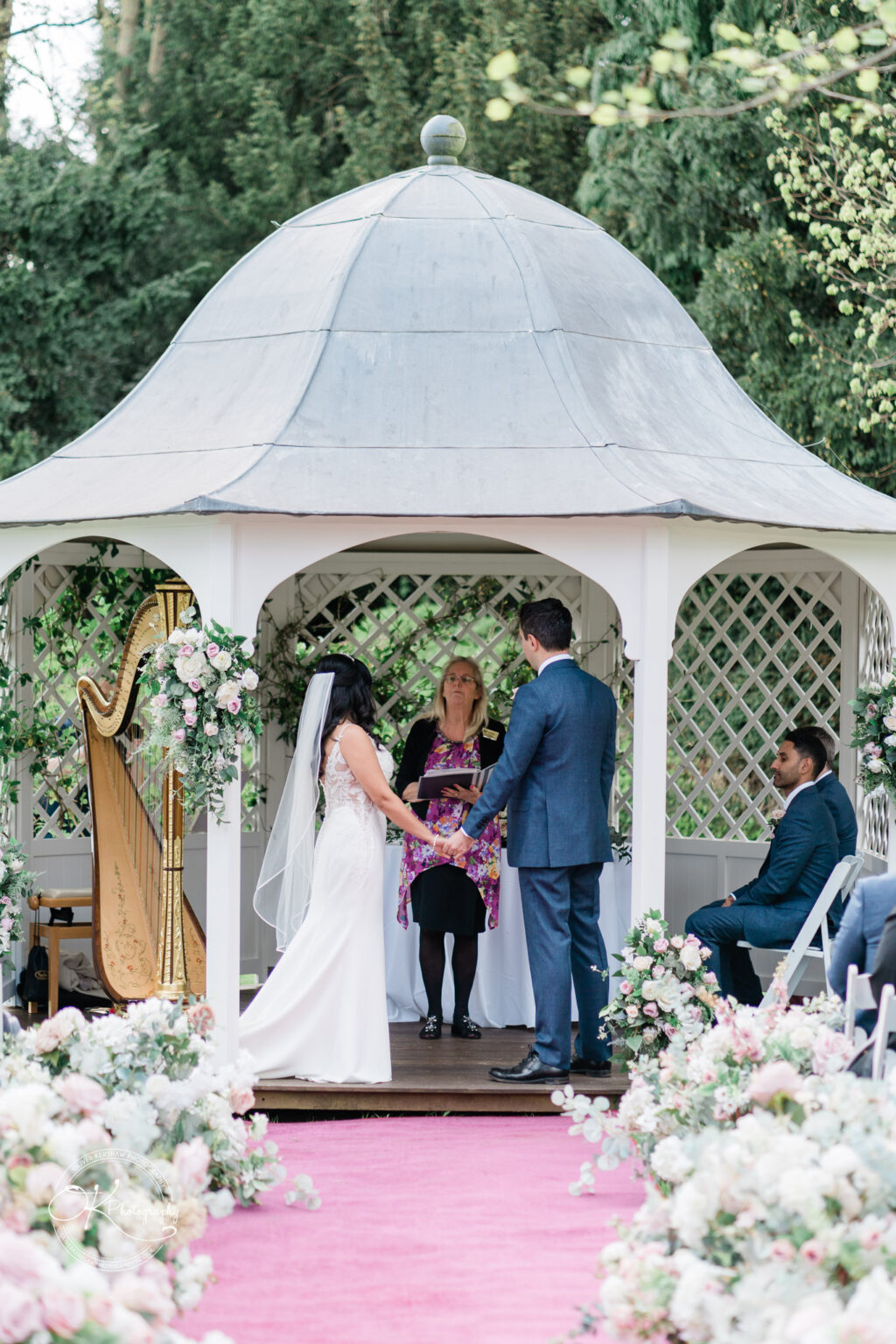 Bride and groom exchanging vows under a gazebo at Prestwold Hall