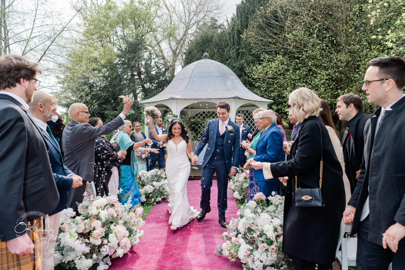 Bride and groom walking down the aisle as guests cheer at Prestwold Hall