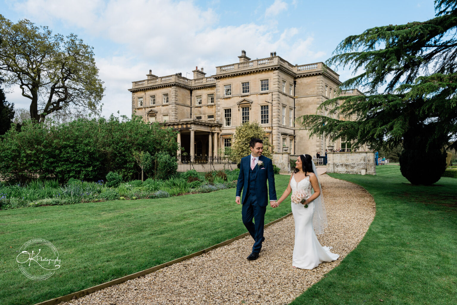 Bride and groom walking on the garden path of Prestwold Hall.