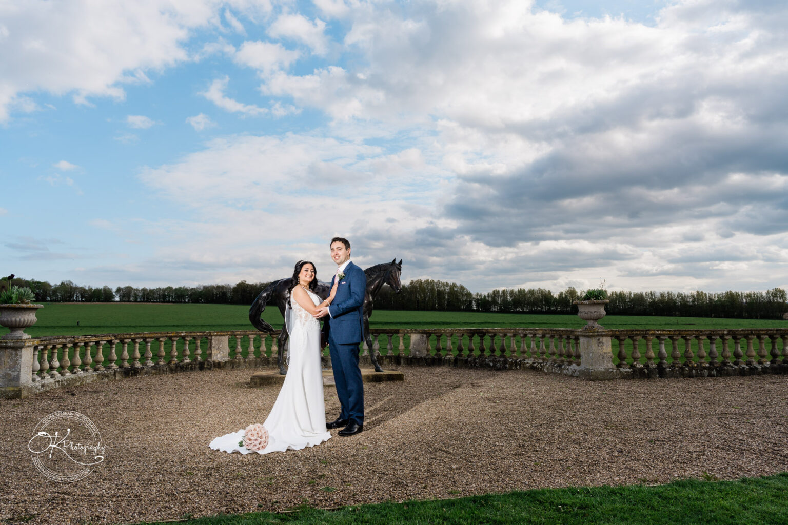 Bride and groom posing with the horse statue at Prestwold Hall.