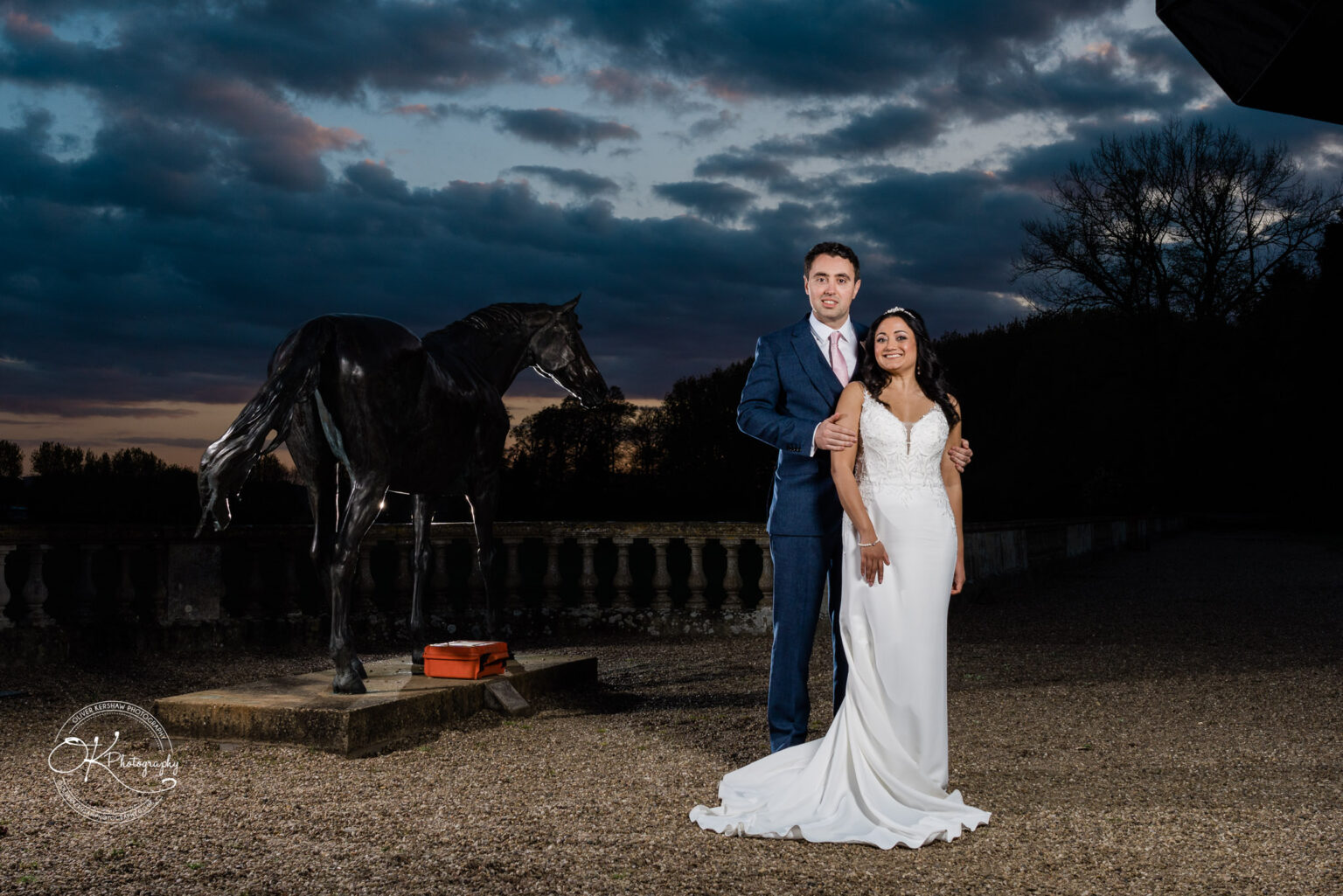 Bride and groom in front of a horse statue at sunset during the wedding reception.
