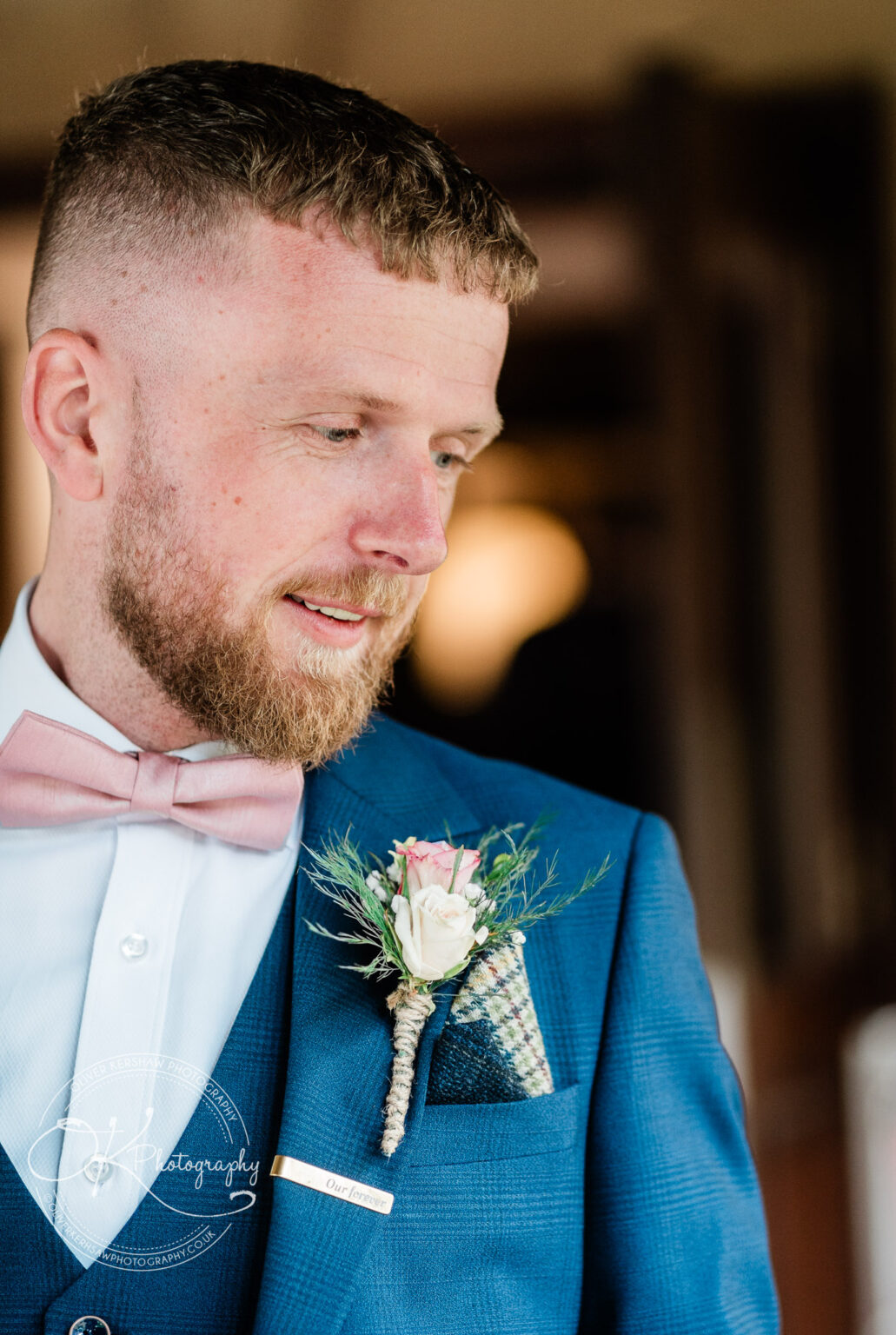Man in a blue suit with a pink bow tie and boutonniere.