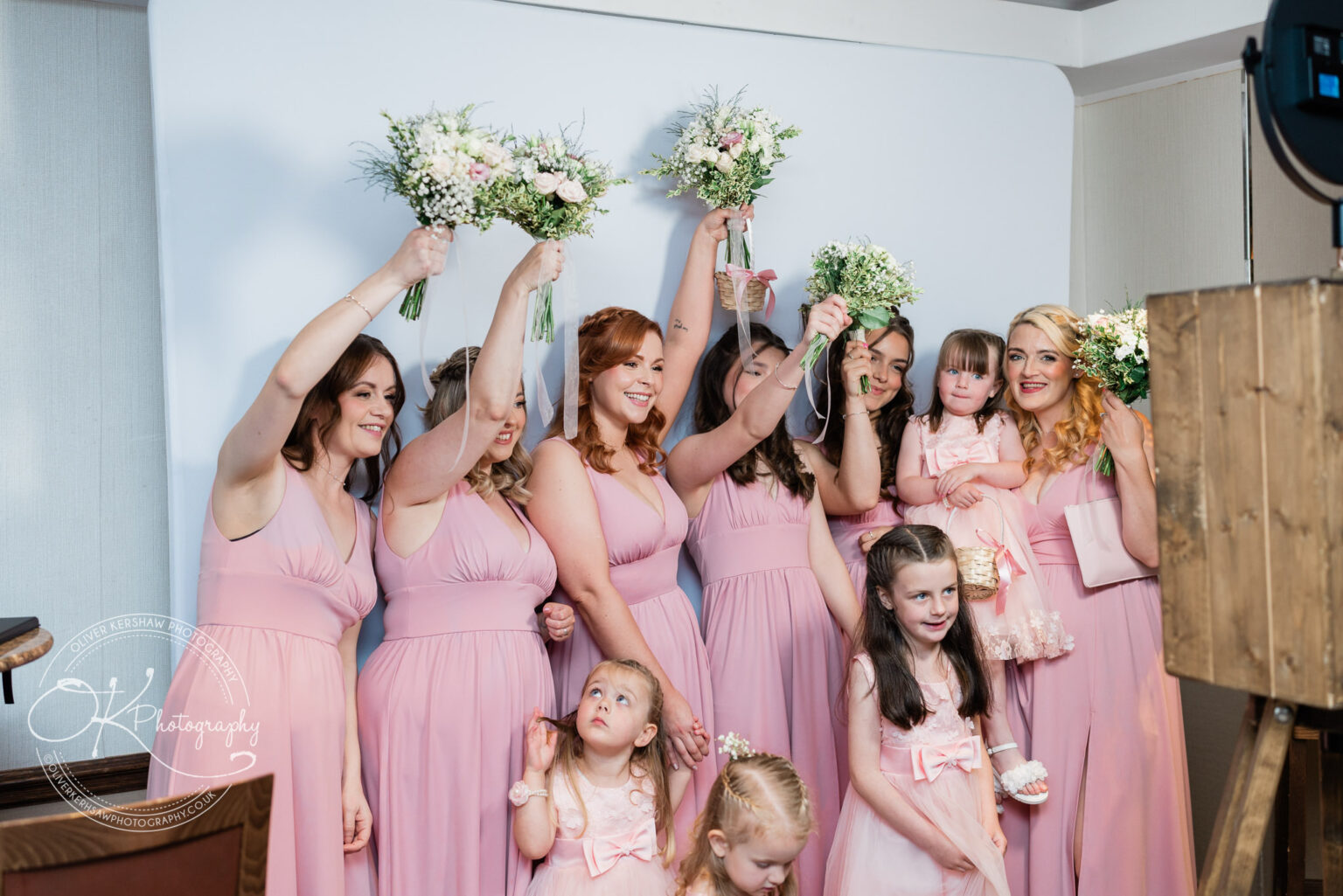 Bridesmaids in pink dresses posing with flower bouquets, accompanied by young girls in matching outfits.