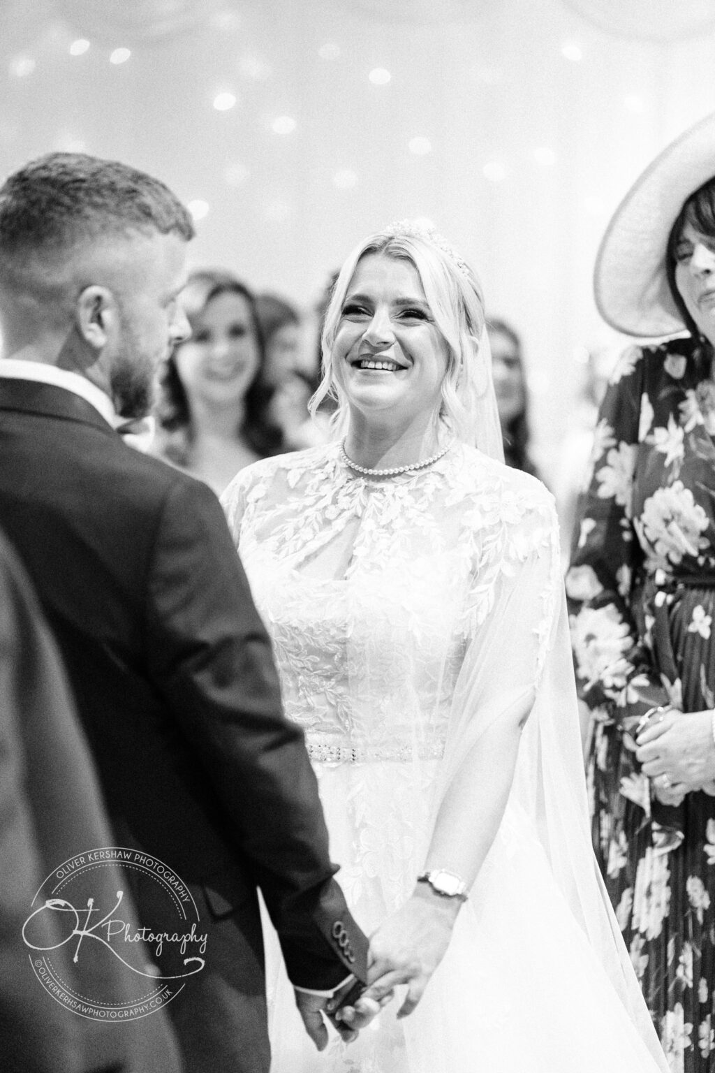 Bride and groom holding hands and smiling during a wedding ceremony.