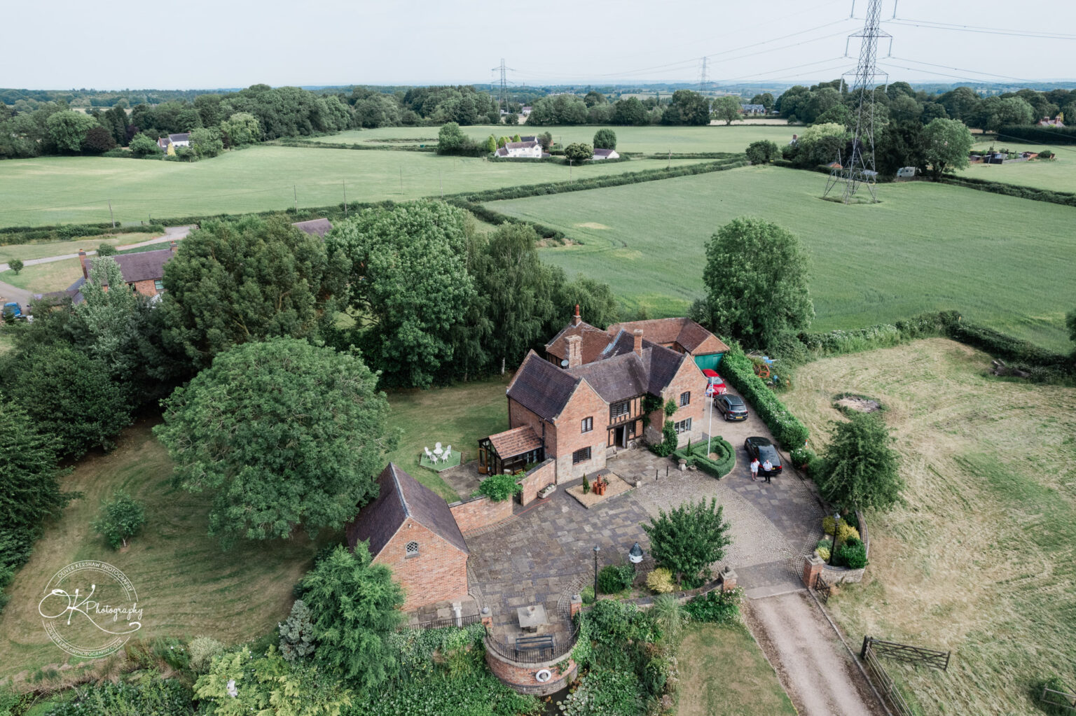 Aerial view of Little Markfield Farm, showcasing the rustic house, surrounding greenery, and fields in the countryside.