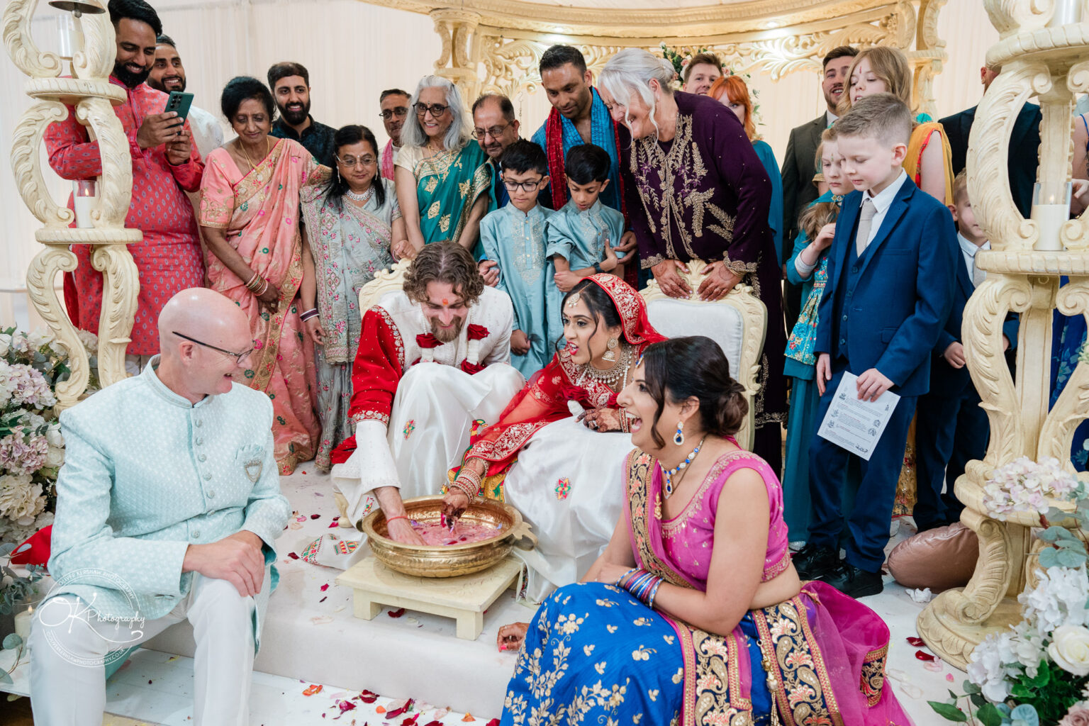 A wedding ceremony taking place at Winstanley House, featuring a couple in traditional attire, surrounded by family and friends in vibrant clothing.