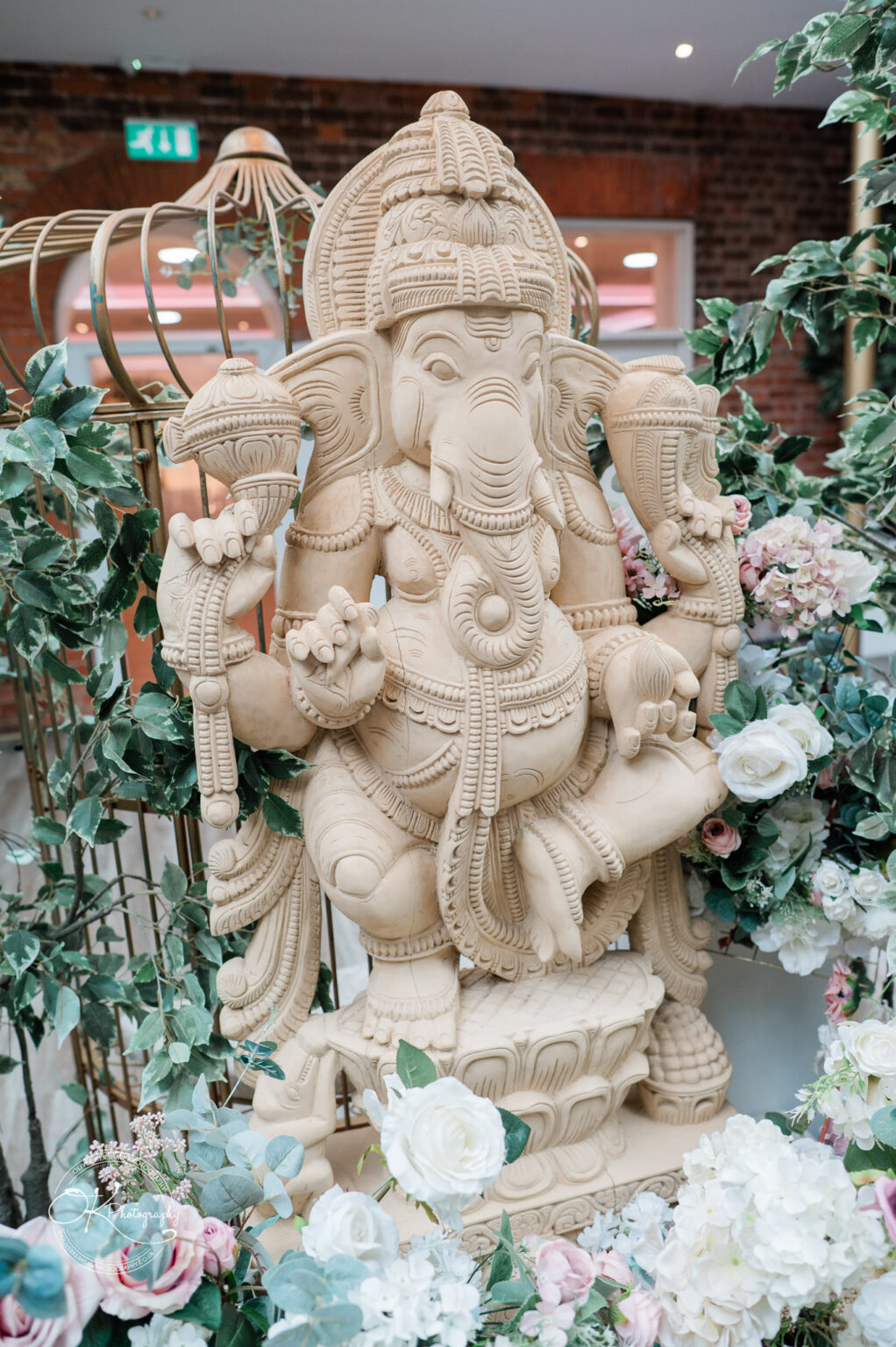 A detailed statue of Ganesh surrounded by floral arrangements, adding elegance to the wedding decor at Winstanley House.
